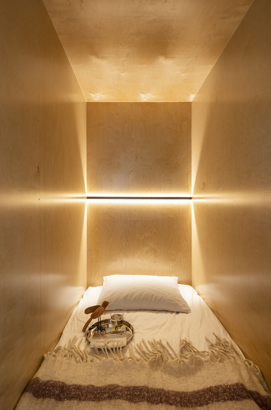 Sleeping alcove lit by a horizontal line of warm cove light